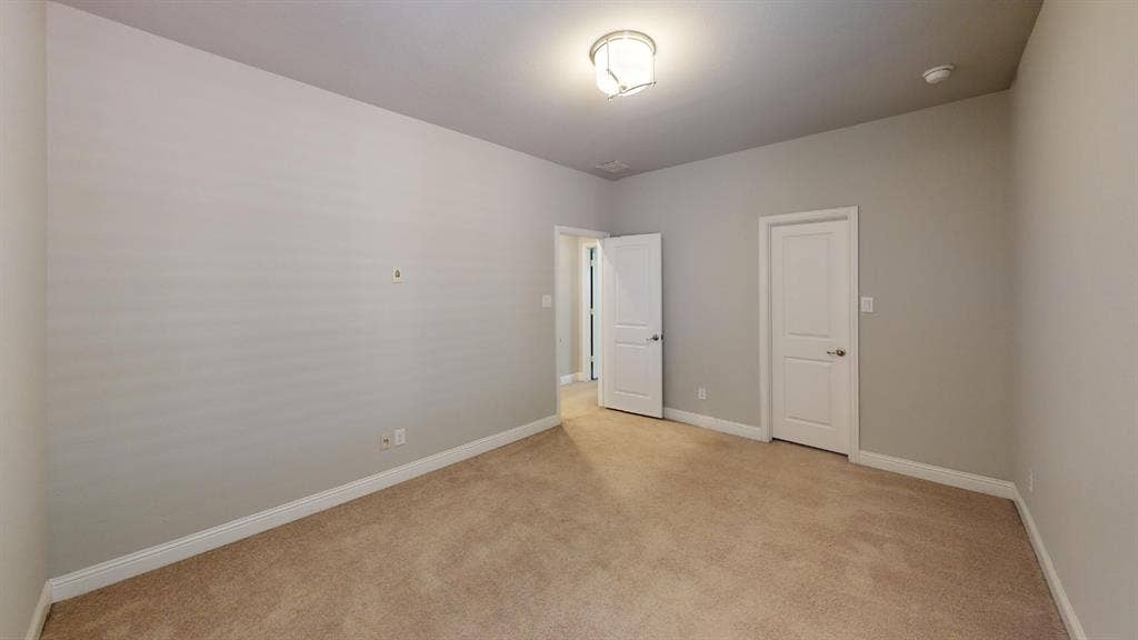 7005 Golf Club Drive, McKinney, TX 75070 Neutral wall-toned room featuring beige carpeting, neutral wall paint, a six-panel door, and a flush-mount ceiling light fixture