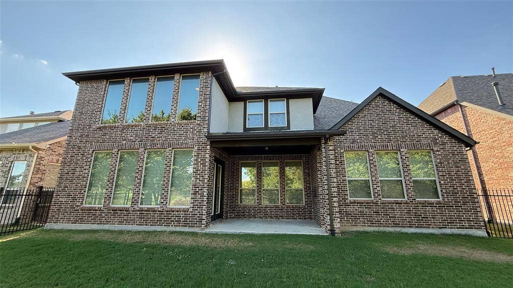 7005 Golf Club Drive, McKinney, TX 75070 Two-story brick exterior featuring a covered patio, multi-pane windows, and black metal perimeter fencing