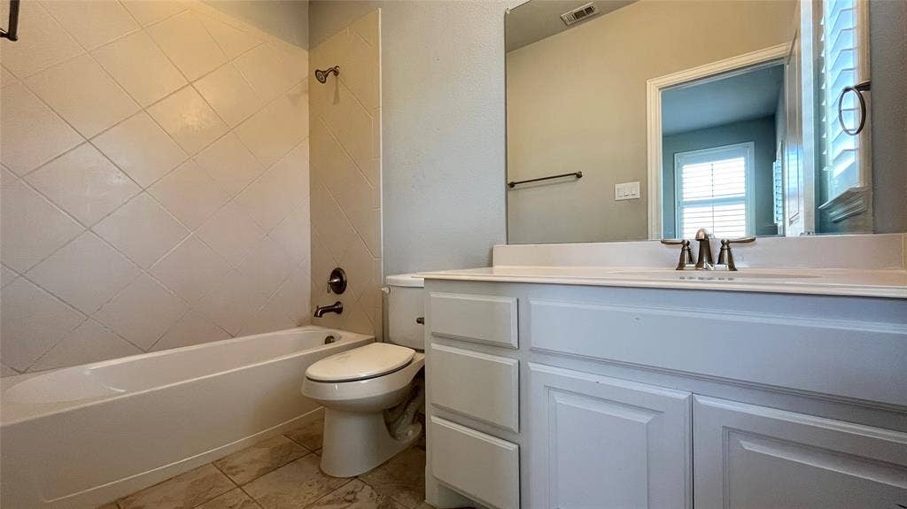 7005 Golf Club Drive, McKinney, TX 75070 Bathroom featuring a white vanity cabinet with a solid surface countertop, diagonal-set wall tile surrounding the bathtub, tile flooring, and a large wall-mounted mirror