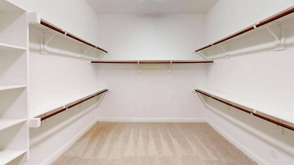 7005 Golf Club Drive, McKinney, TX 75070 Walk-in closet featuring white built-in shelving, wooden closet rods, and neutral carpeting