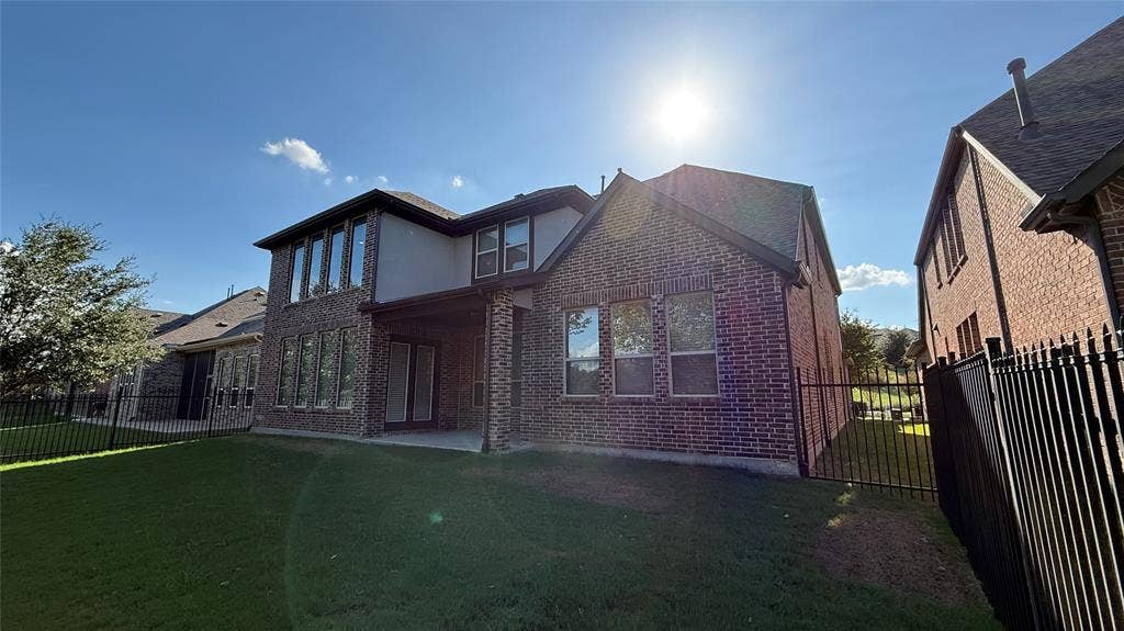7005 Golf Club Drive, McKinney, TX 75070 Multi-story brick exterior featuring a covered patio, expansive windows, and a metal perimeter fence