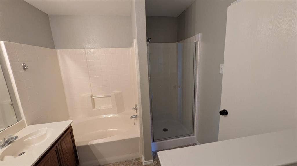408 Oxford Loop Loop, Princeton, TX 75407 Bathroom featuring a separate soaking tub and glass-enclosed shower stall, wood-finish vanity cabinet, integrated sink, and wall-mounted mirror