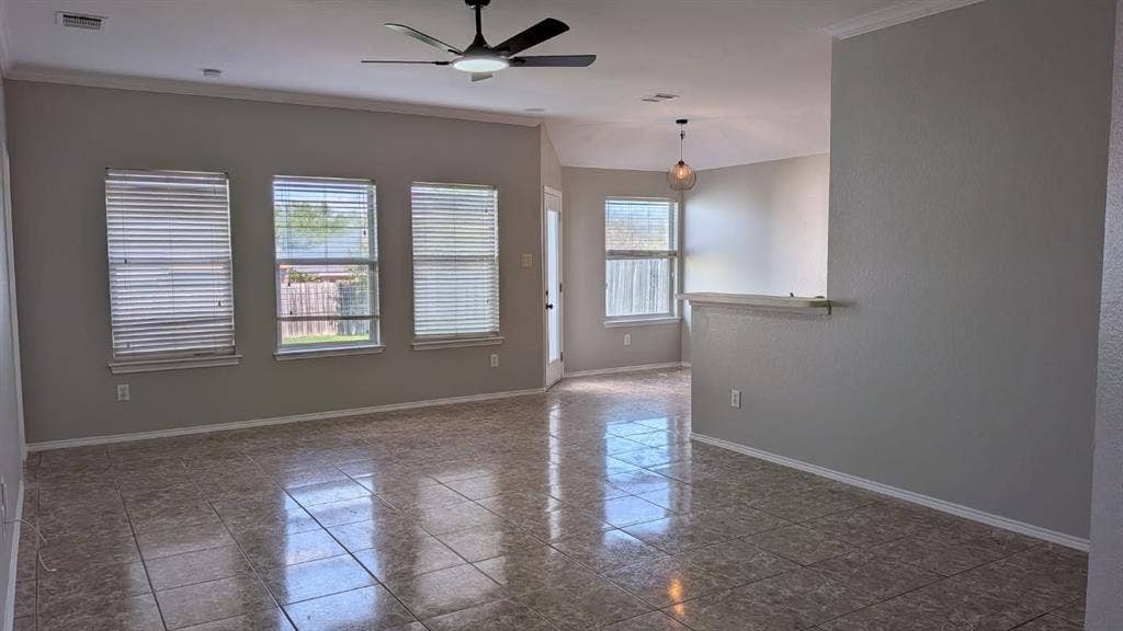 408 Oxford Loop Loop, Princeton, TX 75407 Living area featuring tile flooring, neutral wall paint, three large windows with horizontal blinds, a ceiling fan with integrated lighting, and a partial height wall divider