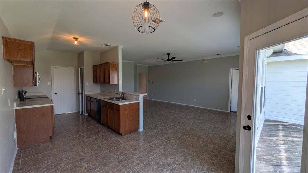 408 Oxford Loop Loop, Princeton, TX 75407 Open-concept interior featuring tile flooring, wood cabinetry, stainless steel sink with pull-down faucet, cage-style pendant lighting, and ceiling fan