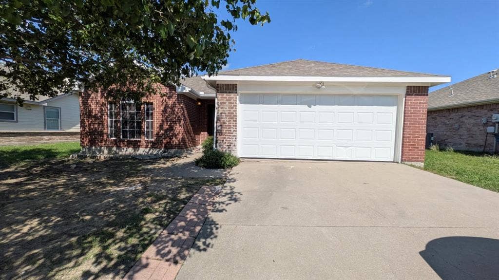 408 Oxford Loop Loop, Princeton, TX 75407 Single-story residence featuring a brick exterior, shingled roof, attached two-car garage, concrete driveway, and front-facing multi-pane windows