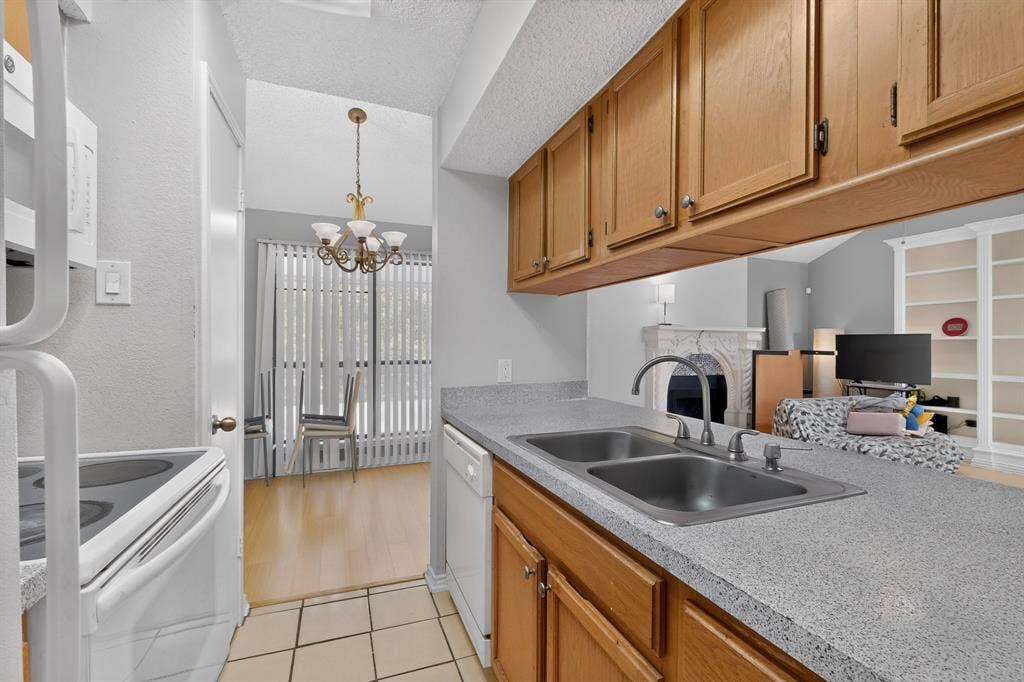 5750 Phoenix Drive, #6, Dallas, TX 75231 Kitchen featuring light wood cabinetry, dual-basin stainless steel sink, and light speckled countertops