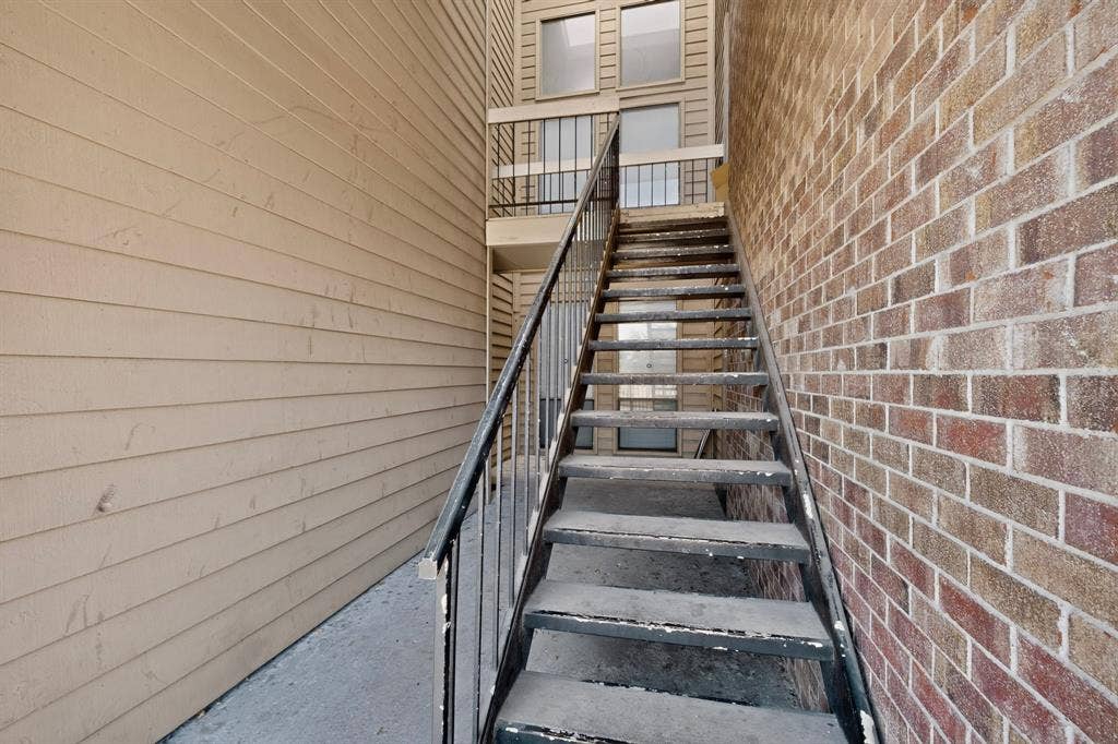 5750 Phoenix Drive, #6, Dallas, TX 75231 Exterior staircase with metal railings, brick facade, and horizontal siding