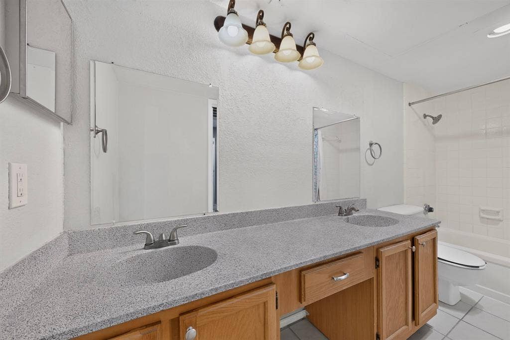 5750 Phoenix Drive, #6, Dallas, TX 75231 Double vanity with integrated sinks, light-toned countertop, wood-finish cabinetry, and a full-size bathtub with shower