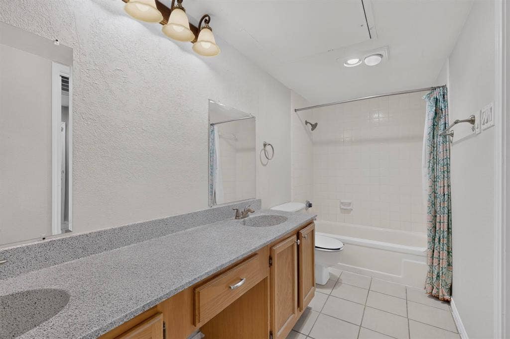 5750 Phoenix Drive, #6, Dallas, TX 75231 Double vanity with integrated sinks and wood-finish cabinetry, tile flooring, and a shower-tub combination