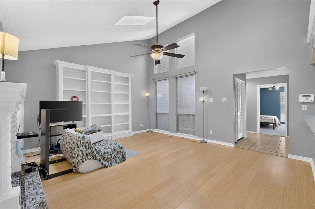 5750 Phoenix Drive, #6, Dallas, TX 75231 Vaulted ceiling with a ceiling fan, recessed windows, wood-finish flooring, built-in shelving, and a tiled fireplace surround