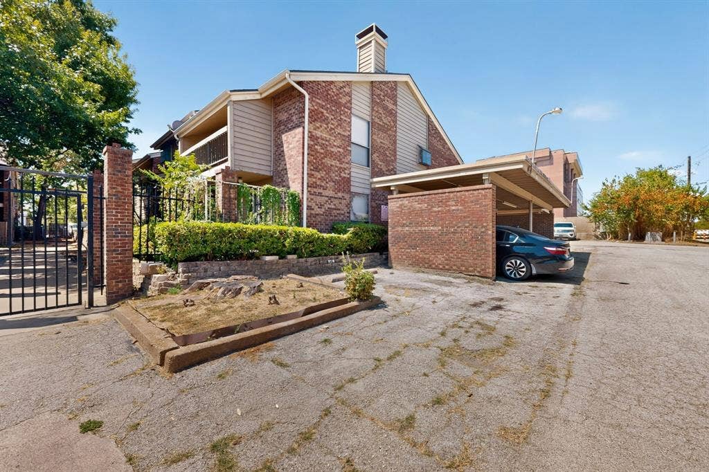 5750 Phoenix Drive, #6, Dallas, TX 75231 Brick exterior with siding accents, a prominent brick chimney, and an integrated carport structure