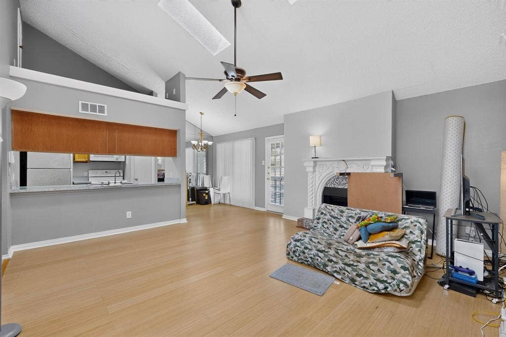 5750 Phoenix Drive, #6, Dallas, TX 75231 Vaulted ceilings, wood-finish flooring, a decorative fireplace, and an open-concept pass-through to the kitchen with a breakfast bar