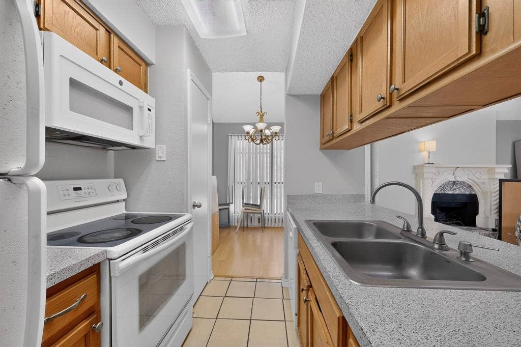 5750 Phoenix Drive, #6, Dallas, TX 75231 Kitchen with wood cabinetry, light-toned countertops, and a double basin sink