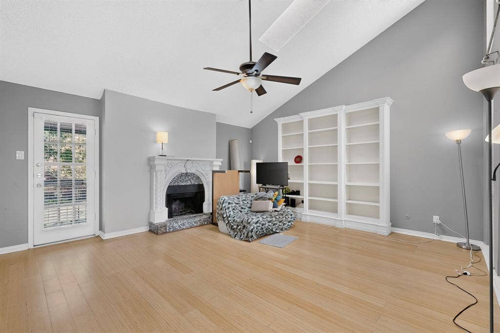 5750 Phoenix Drive, #6, Dallas, TX 75231 Vaulted ceiling, wood-finish flooring, ceiling fan, ornate fireplace with a marble-finish surround, and built-in shelving