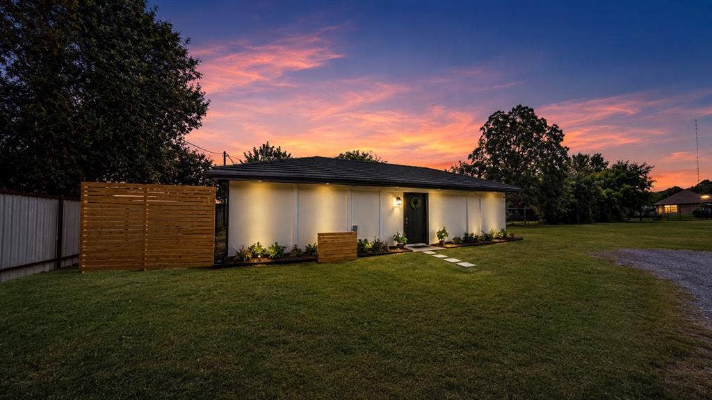 Single-story exterior featuring white siding, a hip roof, horizontal wood privacy fencing, and stone paver walkway