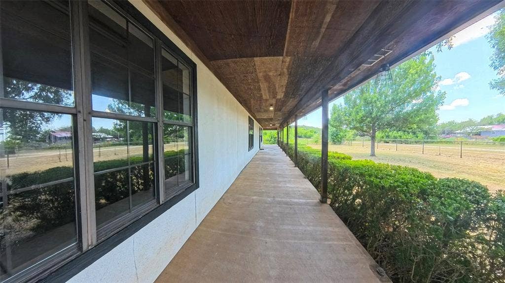 Covered exterior porch featuring wood-plank ceiling, concrete flooring, and grid-pattern window panes