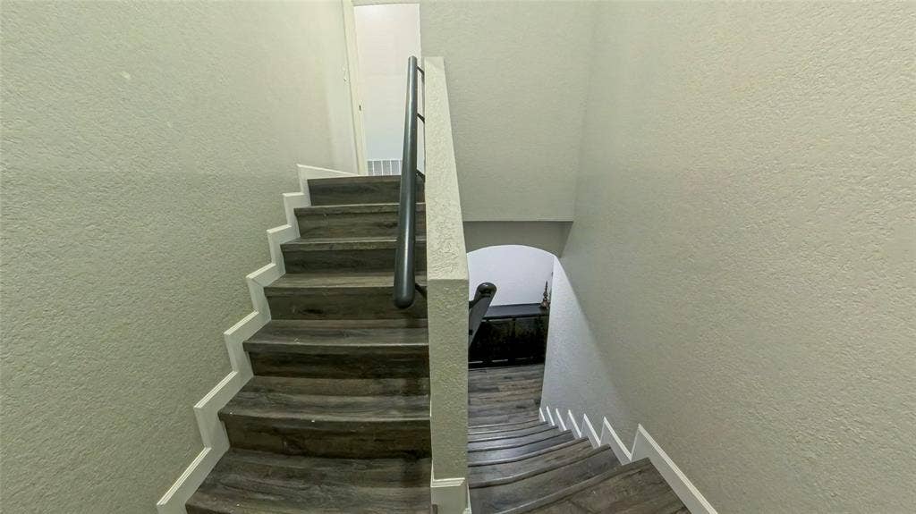 Staircase featuring wood-finish treads and a dark metal handrail