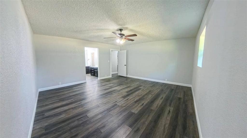Spacious interior featuring wood-finish flooring, a ceiling fan with light fixture, and textured ceilings