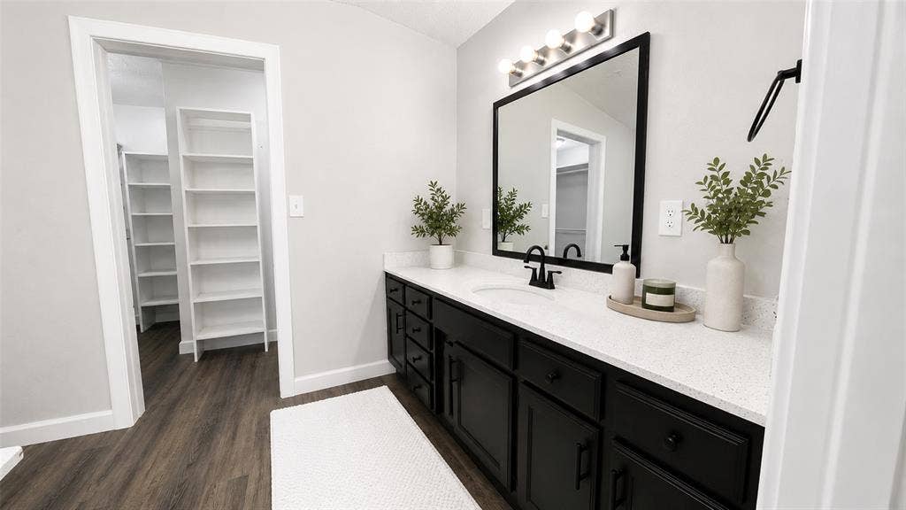 Bathroom featuring a dual-tone vanity with black cabinetry, a white countertop, an integrated oval sink, and a matte black faucet