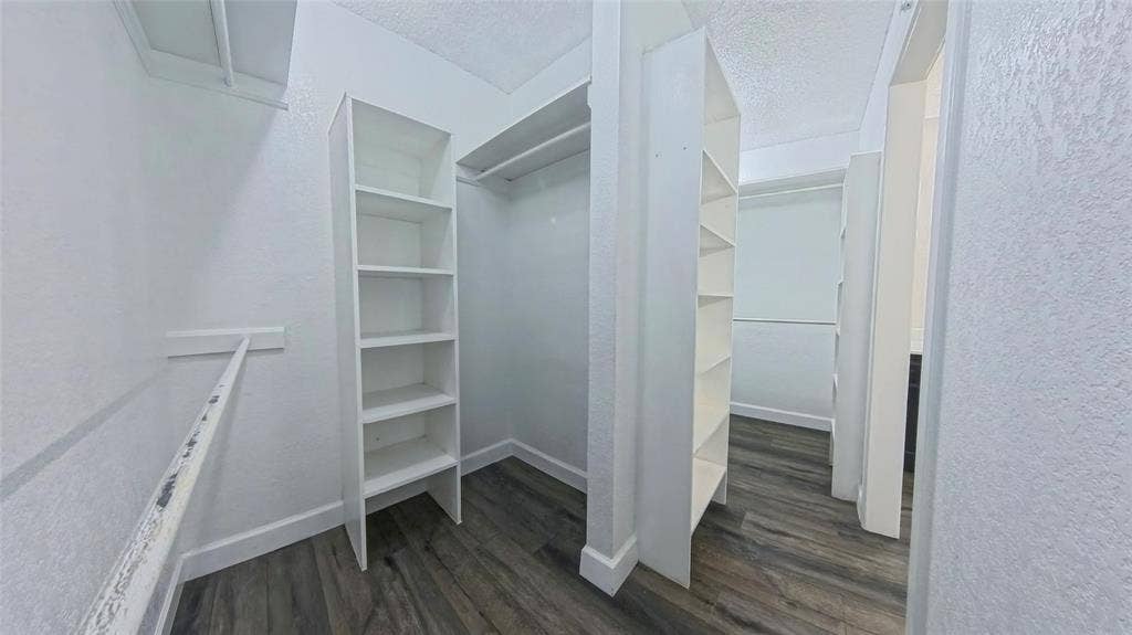 Walk-in closet featuring wood-finish flooring, built-in shelving towers, and multiple hanging rods