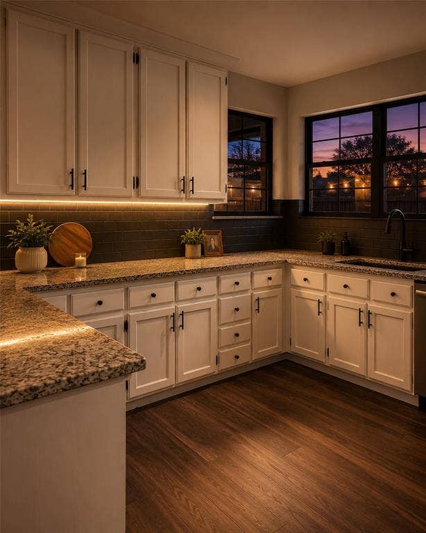 Kitchen featuring white Shaker-style cabinetry, dark stone-finish countertops, subway tile backsplash, matte black hardware, and wood-finish flooring