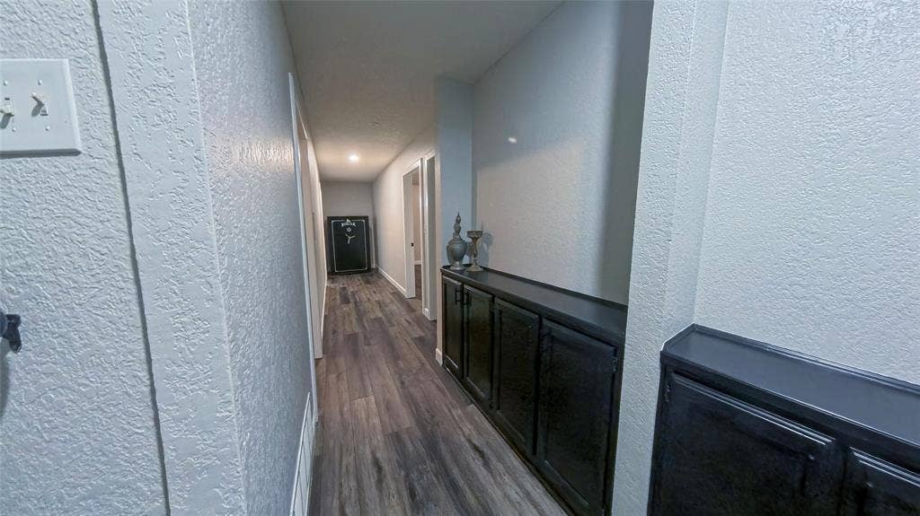 Hallway featuring wood-finish flooring and dark-toned built-in cabinetry with solid-surface countertops