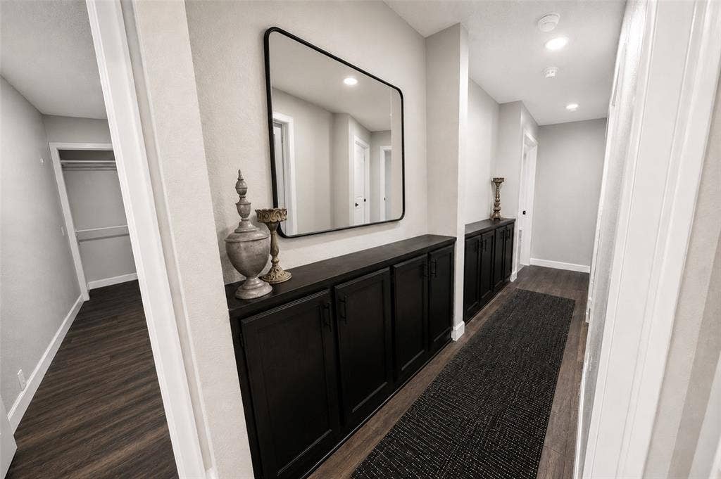 Hallway featuring built-in dark cabinetry with matte black hardware, wood-finish flooring, and recessed lighting