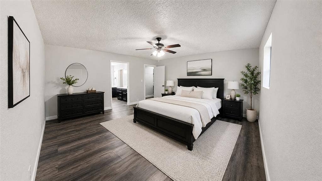 Neutral-toned interior space featuring wood-finish flooring, a multi-blade ceiling fan with integrated lighting, and textured wall surfaces