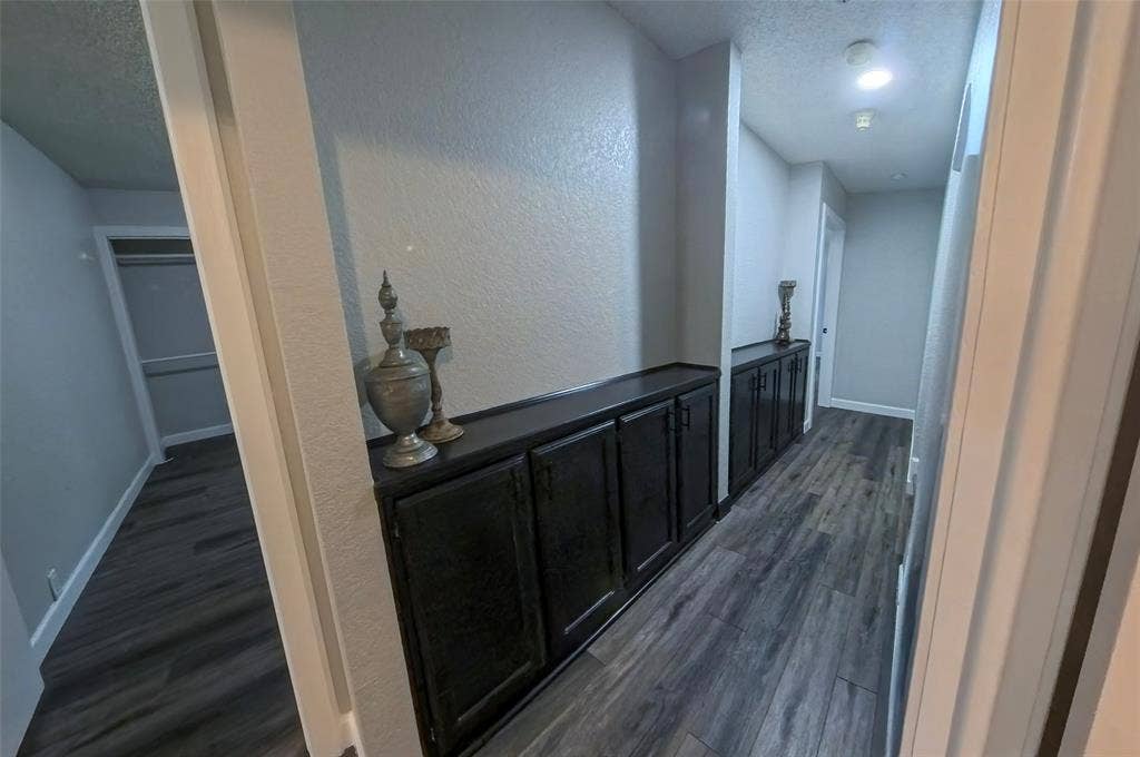 Built-in dark-toned cabinetry with solid-surface countertops, wood-finish flooring, and recessed ceiling lighting