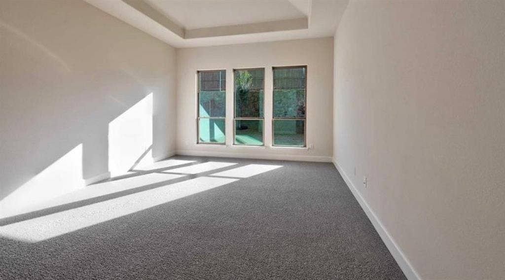Tray ceiling, neutral wall tones, and three large windows featuring grid patterns and exterior exposure