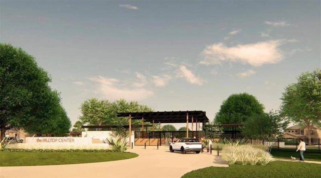 The Hilltop Center featuring a covered pavilion with timber-frame construction, stone accent walls, integrated landscaping, and paved drive entry