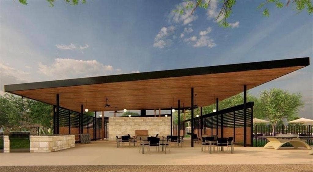 Covered outdoor pavilion featuring a cantilevered roof with wood-finished ceiling, stone-clad fireplace, integrated ceiling fans, and slatted privacy screens