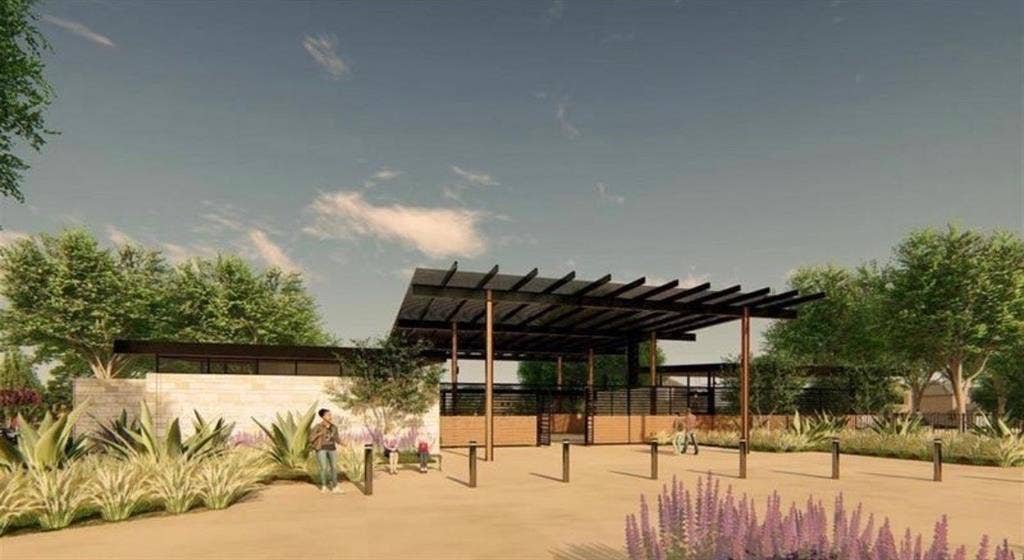 Modern architectural exterior featuring a stone-clad facade, extensive metal pergola structure, and xeriscaped landscaping