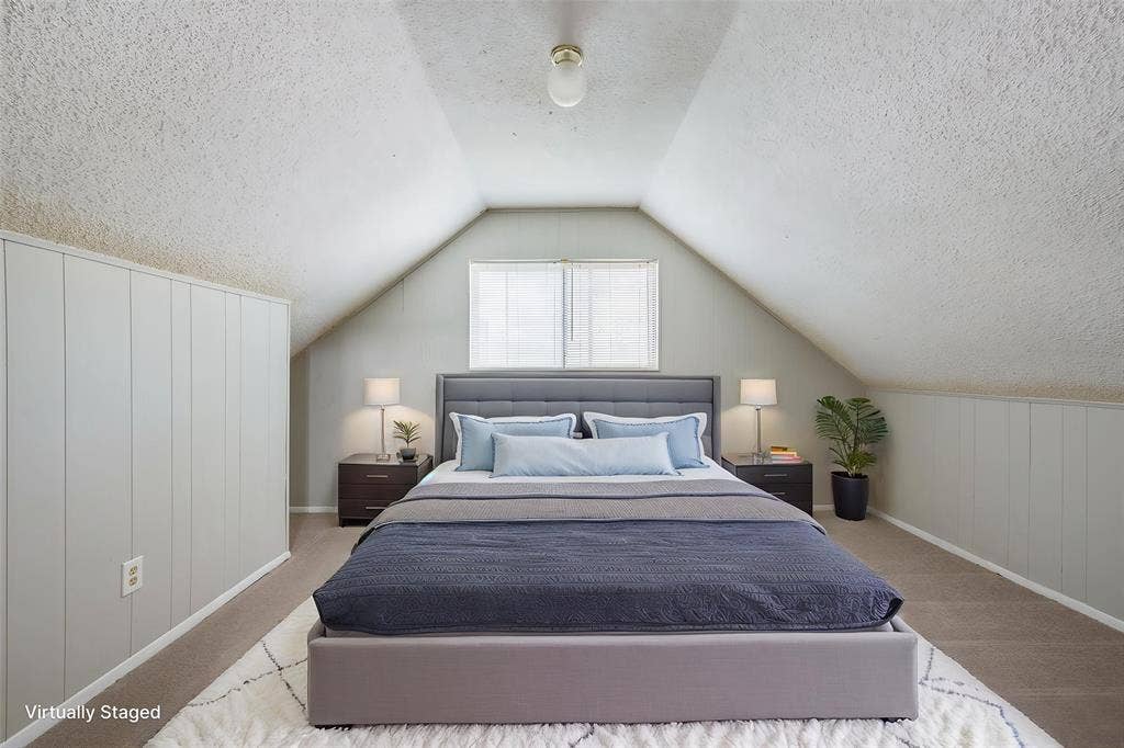 Vaulted ceiling featuring a single flush-mount light fixture and light-toned wall paneling