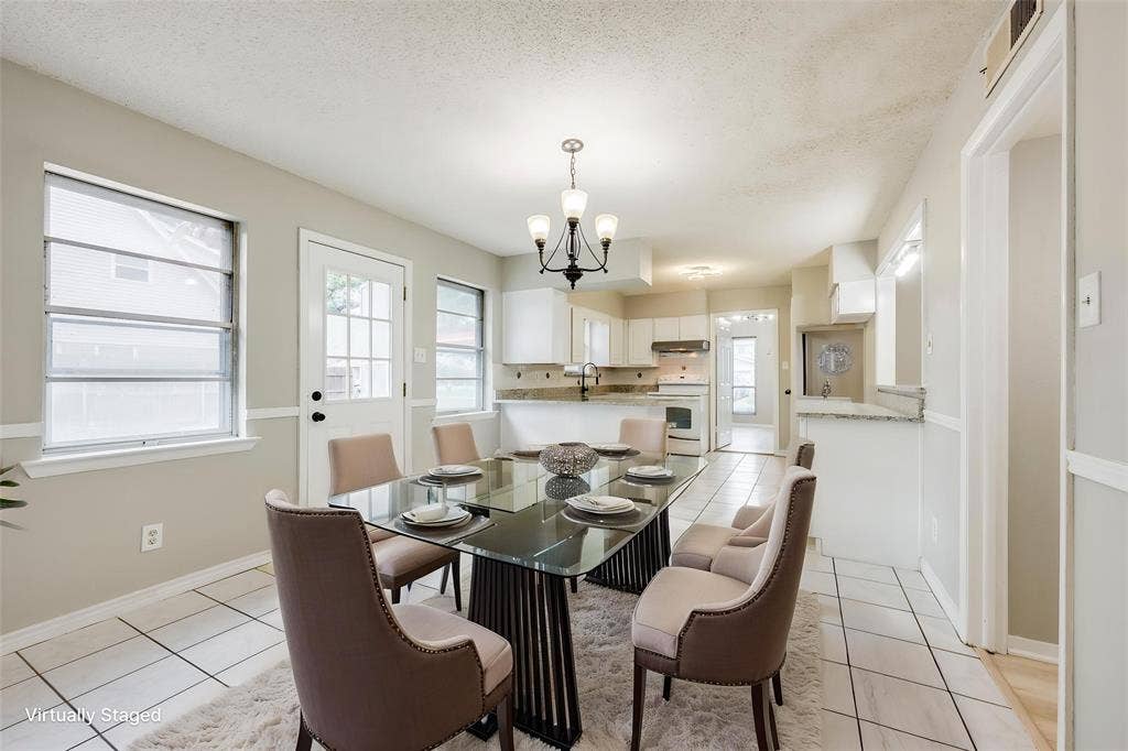 Ceramic tile flooring, multi-pane windows, decorative chandelier, stone-surface counters, and white cabinetry
