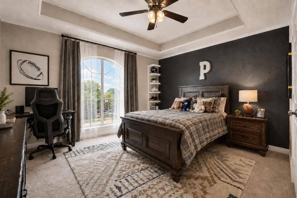 Bedroom featuring a tray ceiling, arched window, built-in shelving, and a dark accent wall
