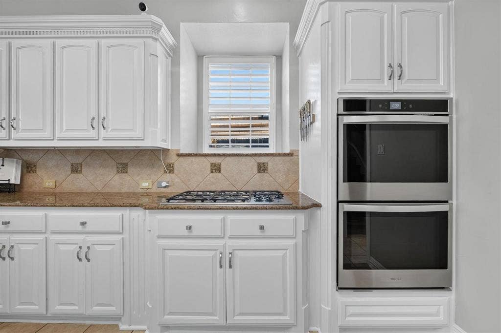 Kitchen featuring white cabinetry, stone-surface countertops, tile backsplash, built-in stainless steel double wall oven, and a gas cooktop