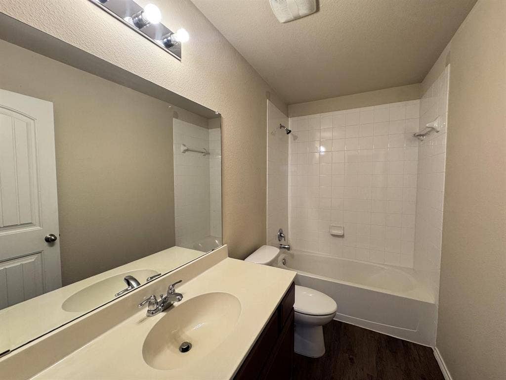2105 Meadow Park Drive, Princeton, TX 75407 Bathroom featuring a vanity with integrated sink, expansive wall-mounted mirror, three-light overhead fixture, and a tub-shower combination with white tile surround