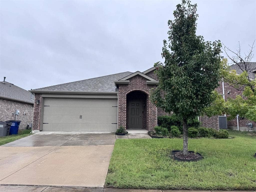 2105 Meadow Park Drive, Princeton, TX 75407 Brick exterior featuring a covered entryway, a front-facing attached garage, and a manicured lawn with ornamental landscaping
