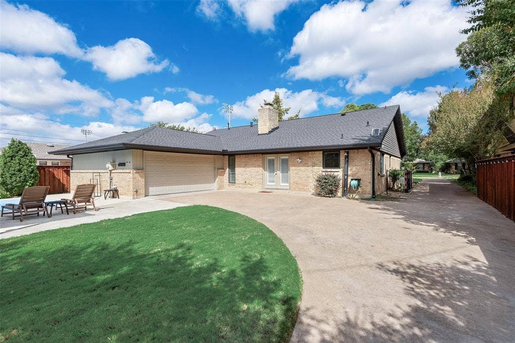 620 Cox Drive, Irving, TX 75062 Brick exterior featuring an attached two-car garage, expansive concrete driveway, double-door entry, and a chimney