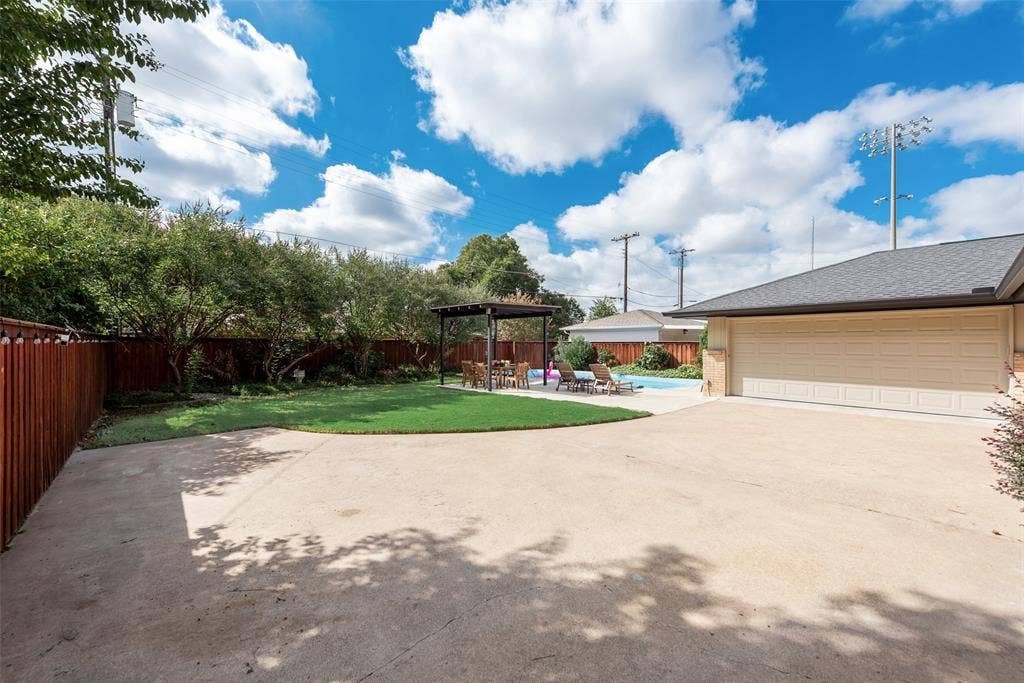 620 Cox Drive, Irving, TX 75062 Backyard featuring a concrete driveway, grass lawn, swimming pool, wood privacy fencing, and a detached pergola