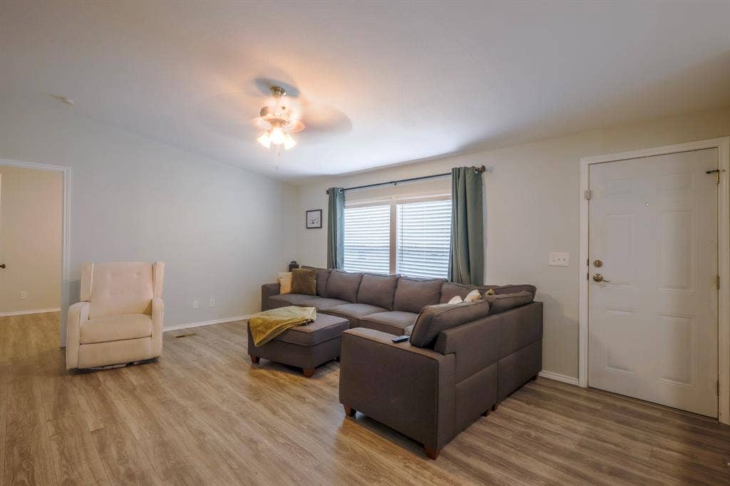 Wood-finish flooring, neutral wall tones, multi-pane window with horizontal blinds, and a ceiling-mounted light fixture