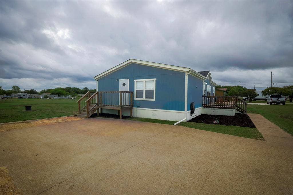 Exterior featuring blue siding, dual wooden elevated decks, and a concrete driveway