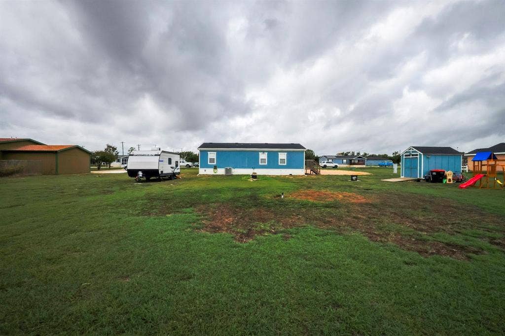Expansive lot featuring a detached storage shed and a blue-sided structure with a dark shingle roof