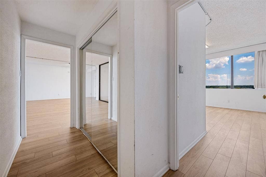 5200 Keller Springs Road, #522, Dallas, TX 75248 Interior featuring wood-finish flooring, sliding mirror-panel closet doors, and floor-to-ceiling windows