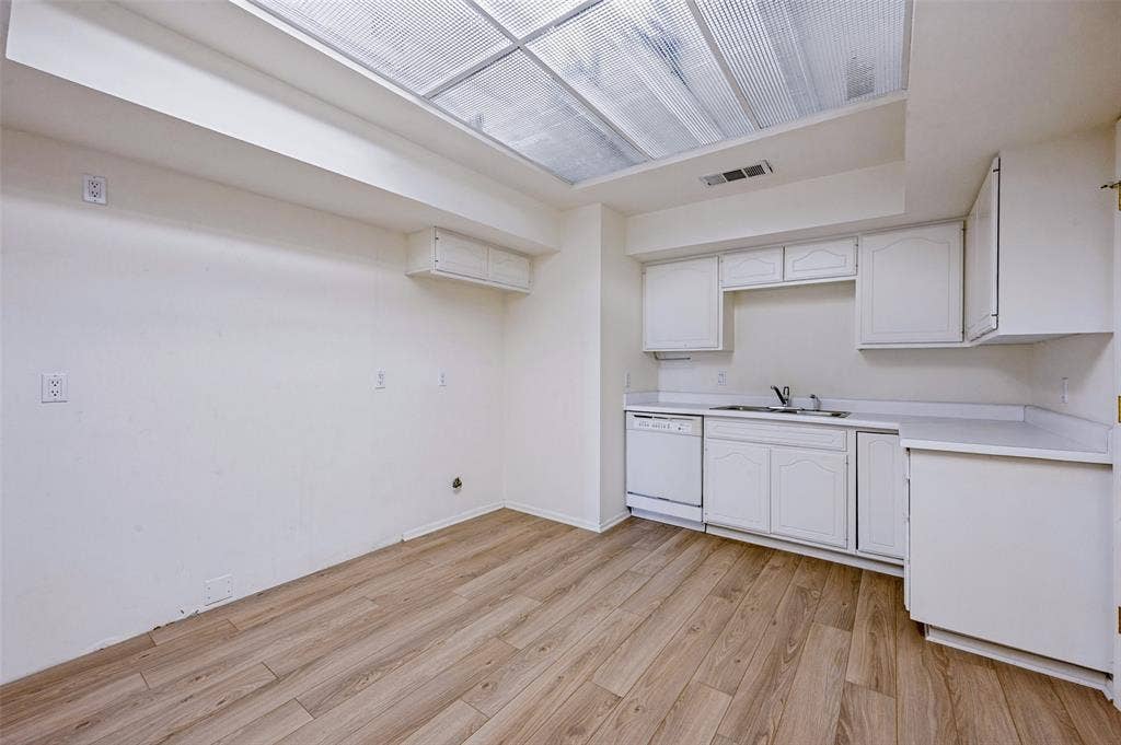 5200 Keller Springs Road, #522, Dallas, TX 75248 Kitchen featuring white cabinetry, wood-finish flooring, a stainless steel sink with a high-arch faucet, a built-in dishwasher, and a recessed ceiling light panel