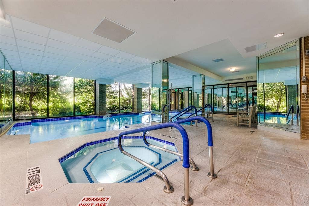 5200 Keller Springs Road, #522, Dallas, TX 75248 Indoor aquatic center featuring a heated lap pool, an integrated jetted spa, floor-to-ceiling glass paneling, and stone-tile flooring