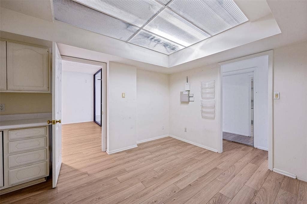 5200 Keller Springs Road, #522, Dallas, TX 75248 Interior space featuring wood-finish flooring, a recessed ceiling panel with integrated lighting, and white built-in cabinetry