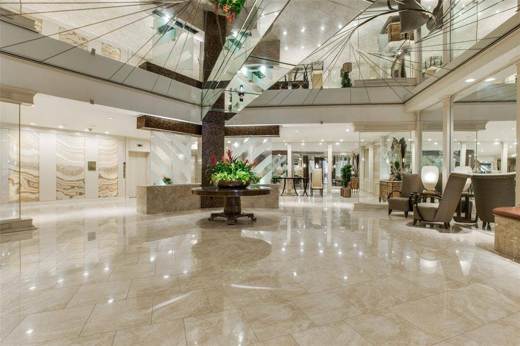 5200 Keller Springs Road, #522, Dallas, TX 75248 Grand lobby featuring polished stone tile flooring, mirrored ceiling accents, recessed lighting, and ornate decorative stone wall panels