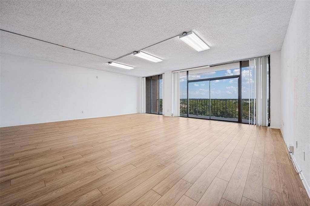 5200 Keller Springs Road, #522, Dallas, TX 75248 Expansive living area featuring wood-finish flooring, sliding glass doors, floor-to-ceiling windows, and linear track lighting